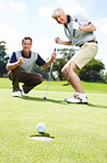 Ball, hole and excited men on golf course together for teamwork, outdoor fun and fitness competition at club. Sports, senior father and son on green for partnership, bonding and support for hobby.