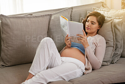 Buy stock photo Shot of a young pregnant woman reading a baby book at home