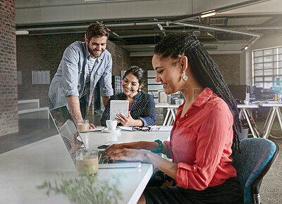 Buy stock photo Shot of a young woman working on a laptop with her colleagues in the background