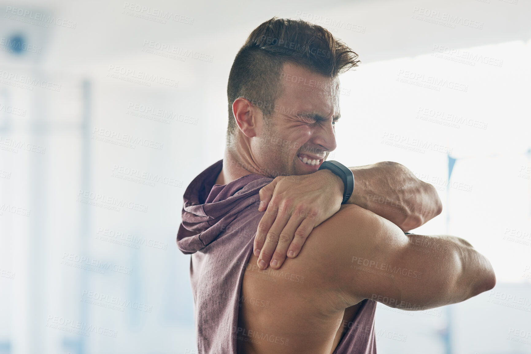 Buy stock photo Shot of a handsome young man stretching at the gym