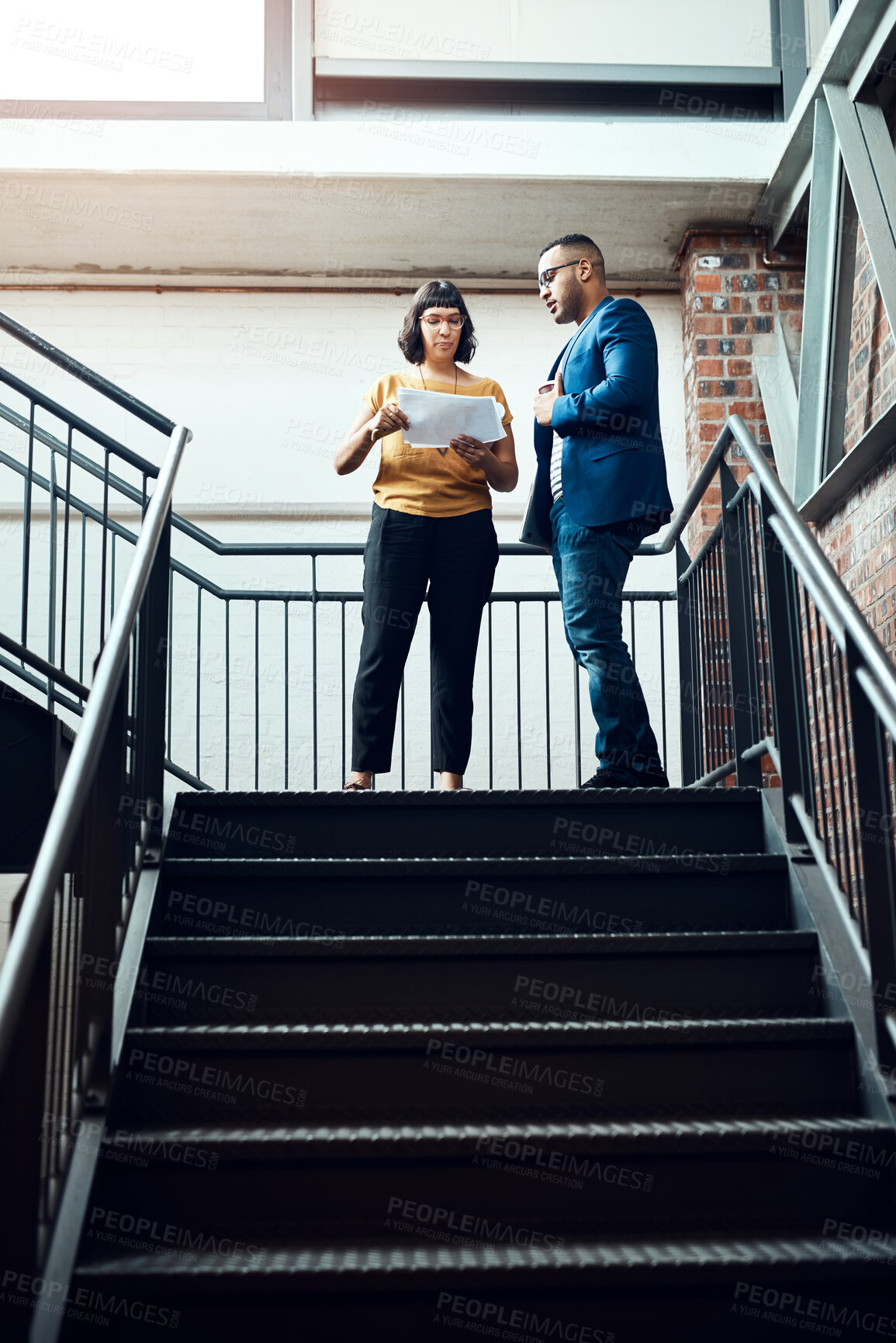 Buy stock photo Shot of two designers having a discussion on a staircase in an office