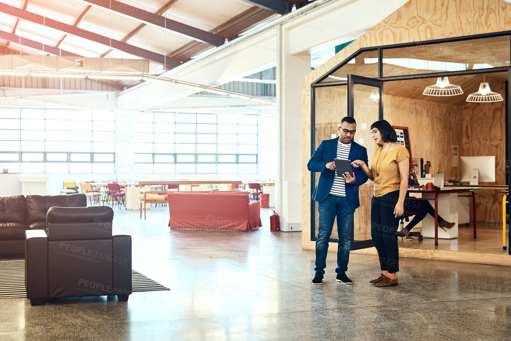 Buy stock photo Shot of two designers working on a digital tablet together in an office