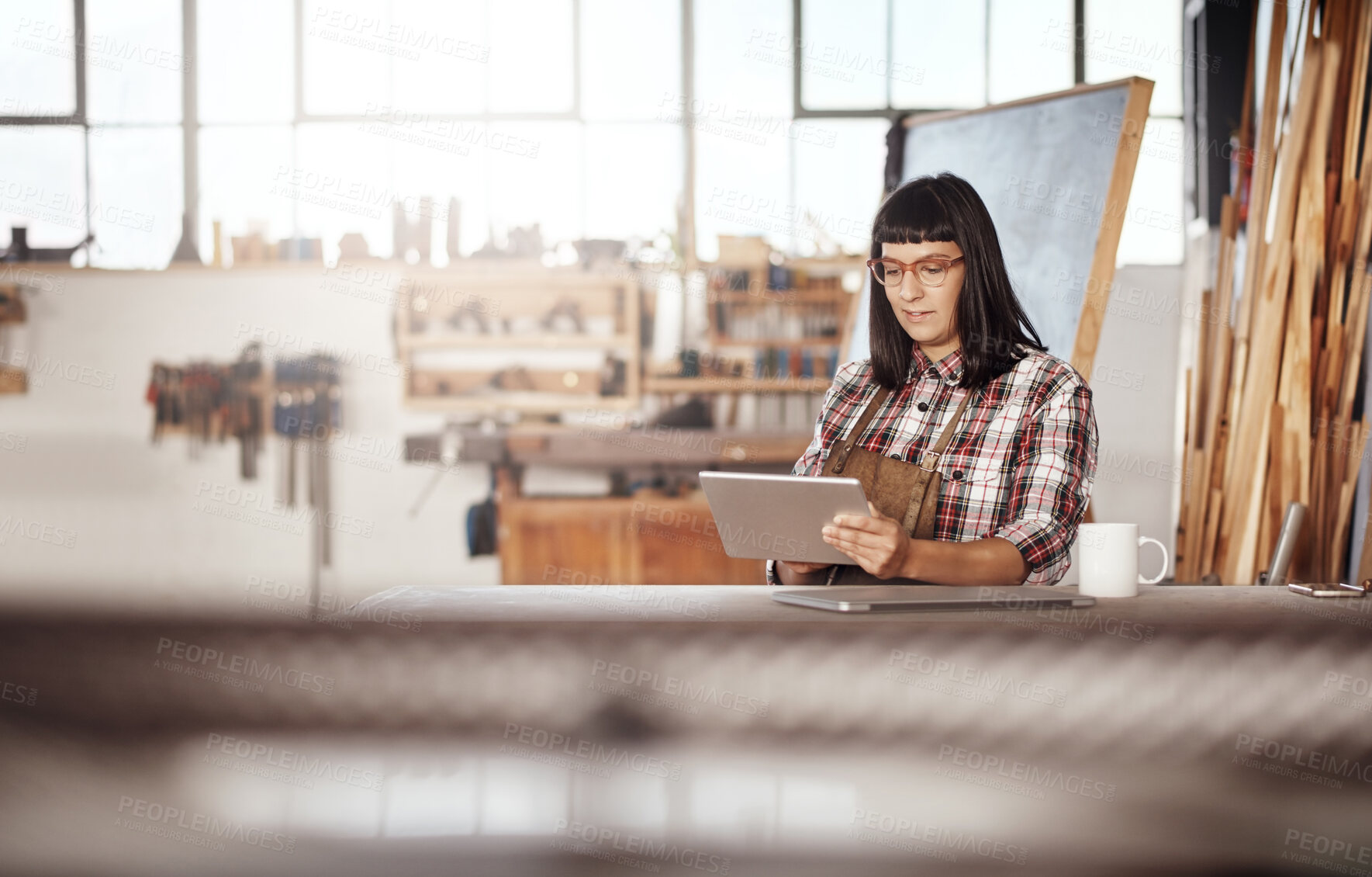 Buy stock photo Cropped shot of an attractive young woman working on her tablet while sitting in her creative workshop