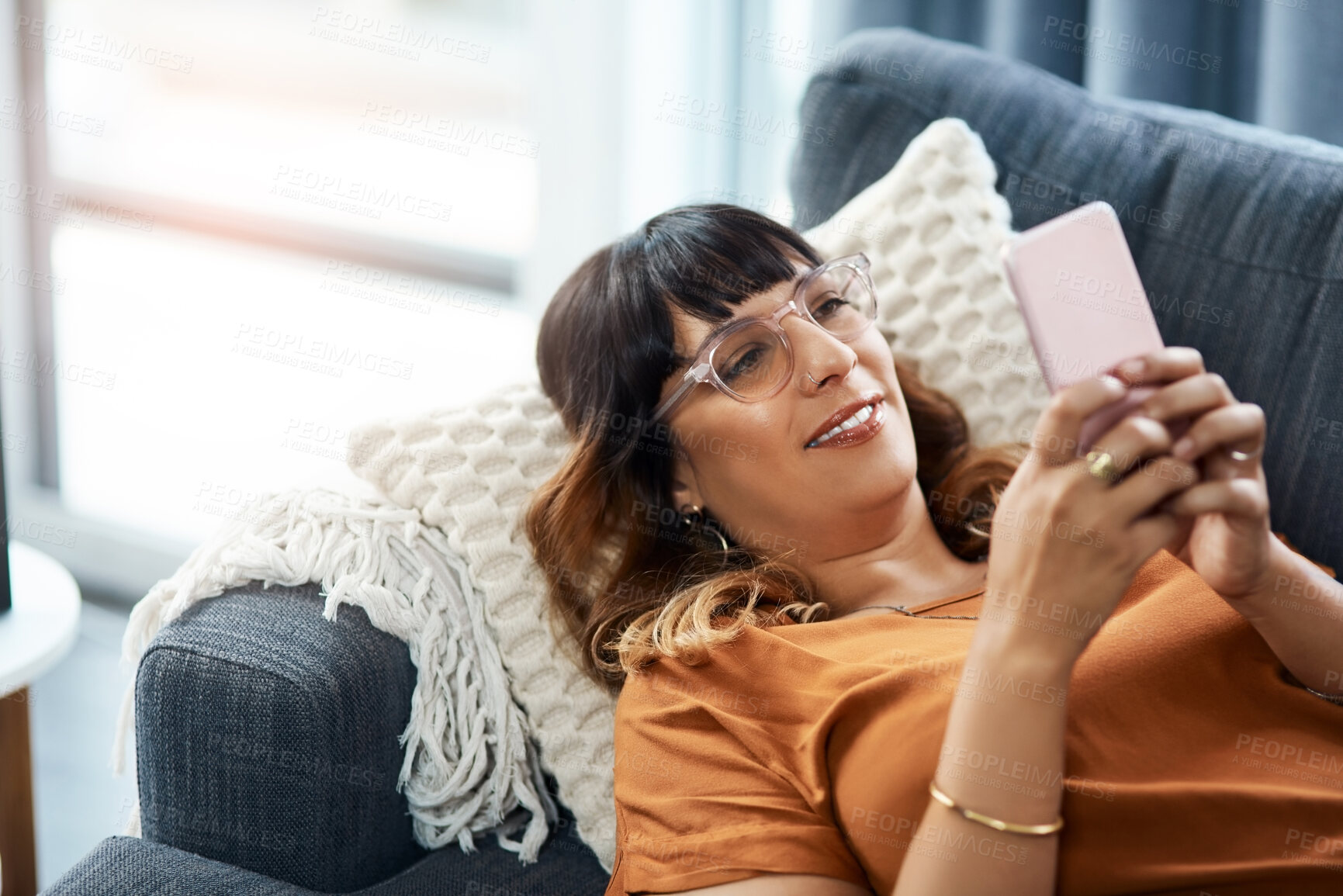 Buy stock photo Smile, woman and relax with phone on sofa for communication, social media and reading ebook on website. Happy, female person and glasses with mobile for online news, typing email and contact at house