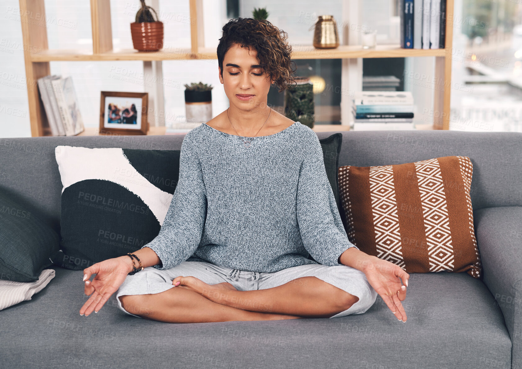 Buy stock photo Full length shot of an attractive young woman sitting and meditating on her sofa in the living room at home