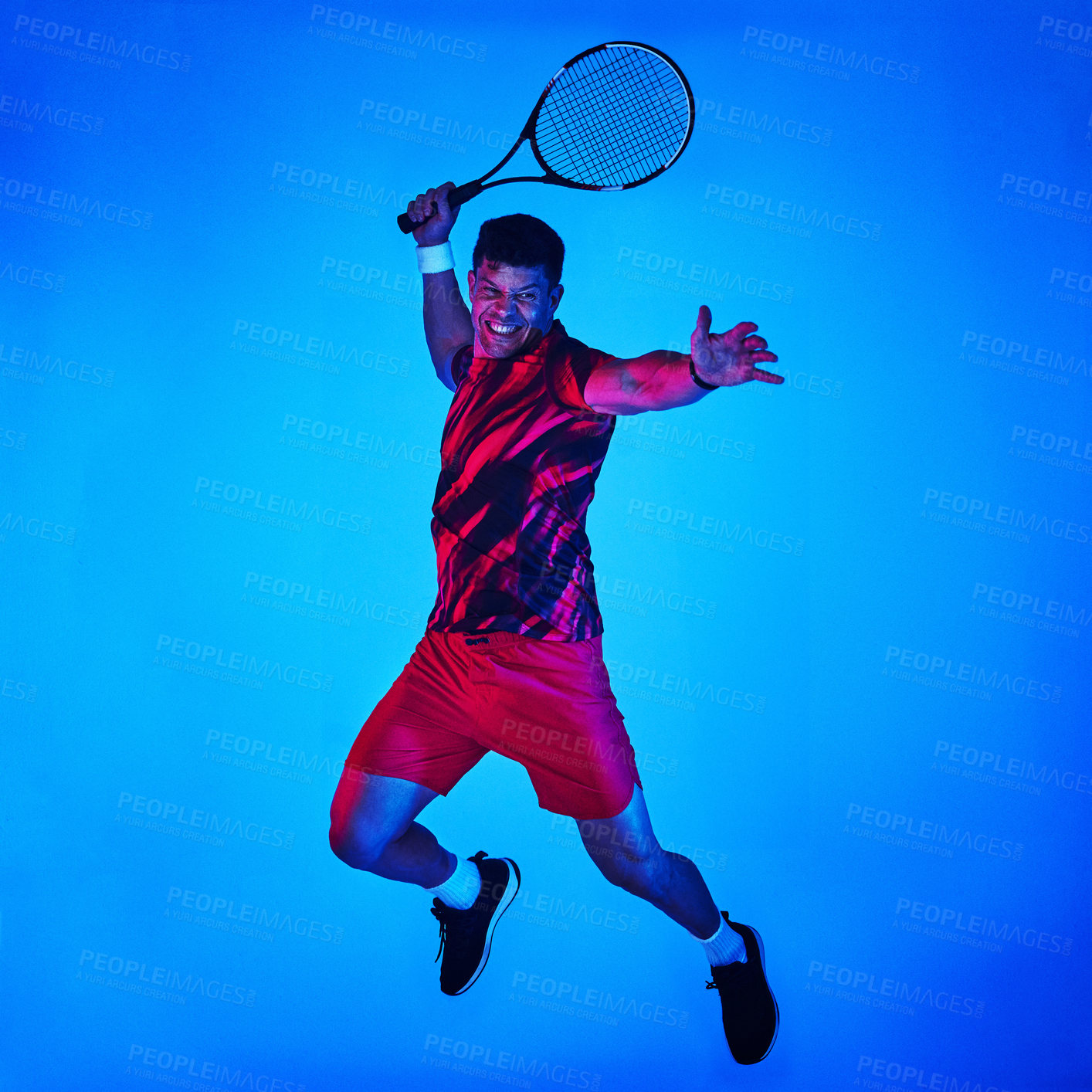 Buy stock photo Man, tennis and strike with jump in studio for sports, game or match on a blue background. Young player, male person or athlete with racket for swing, serve or hit in tournament on mockup space