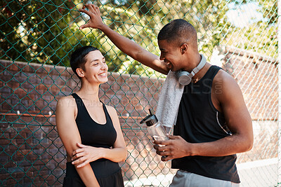 Buy stock photo Shot of two sporty young people chatting to each other against a fence outdoors