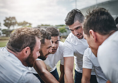 Buy stock photo Cropped shot of a focused young rugby team forming a huddle before a match outside on a rugby field