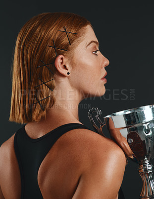 Buy stock photo Woman, sports and trophy in studio for winning, victory and success at competition on grey background. Female person, athlete and serious on confidence with cup for completing tournament on profile