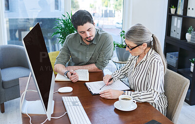 Buy stock photo Shot of two businesspeople going through paperwork together in an office