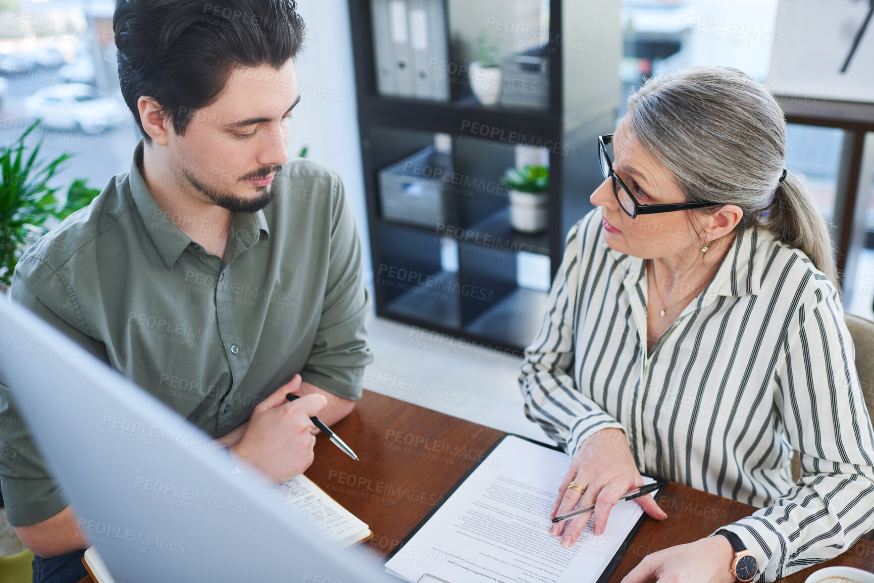 Buy stock photo Shot of two businesspeople going through paperwork together in an office