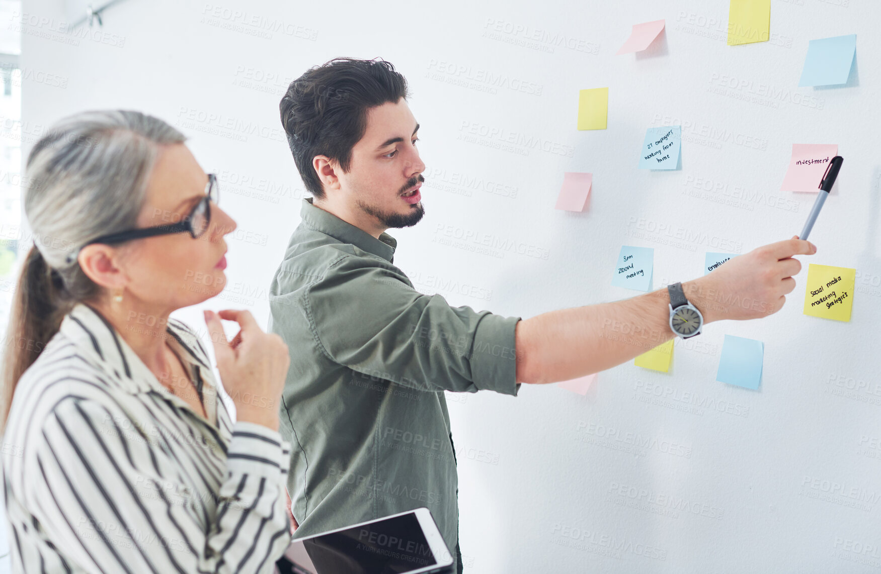 Buy stock photo Shot of two businesspeople brainstorming with notes on a wall in an office