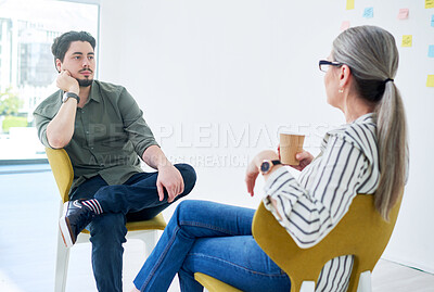 Buy stock photo Shot of two businesspeople having a discussion while sitting on chairs in an office