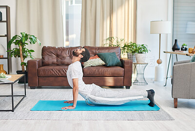 Buy stock photo Shot of a handsome young man practising yoga in his living room at home