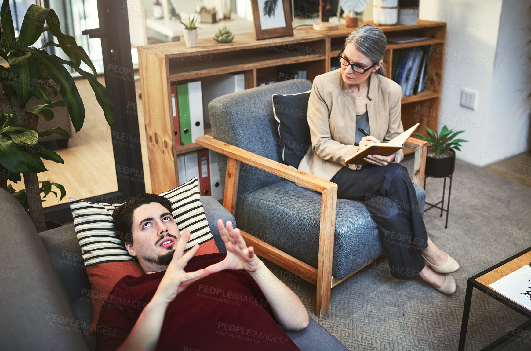 Buy stock photo Shot of a young man having a therapeutic session with a psychologist