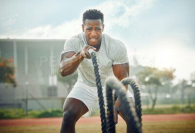 Buy stock photo Cropped shot of a handsome young male athlete exercising with battle ropes outside