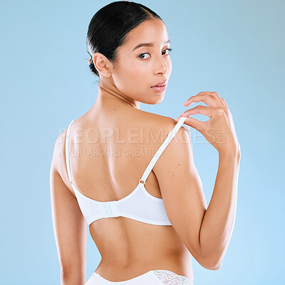 Buy stock photo Studio portrait of an attractive woman looking back over her shoulder while posing in her underwear against a blue background