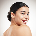 Face of a young beautiful mixed race woman smiling and posing against a grey studio background. Content hispanic female posing against a background