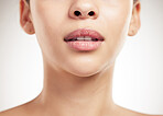 Face of a beautiful woman showing her lips and teeth posing against a grey studio background. Skincare is important. Taking care of dental hygiene