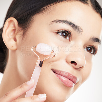 Buy stock photo Beauty, skincare and woman with face roller for results, glow and lymph drainage on gray studio background. Facial, rose quartz and model with stone for dermatology treatment, cosmetics and thinking