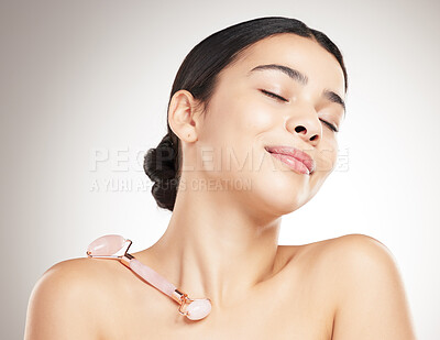 Buy stock photo Calm, skincare and woman with roller for beauty results, peace and massage on gray studio background. Face, rose quartz and model in dermatology treatment, cosmetics and anti aging with eyes closed