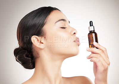 Buy stock photo Woman, kiss and bottle for skincare in studio with facial serum, collagen treatment and dermatology glow. Girl, product and essential oil for aesthetic, beauty and hyaluronic acid on gray background