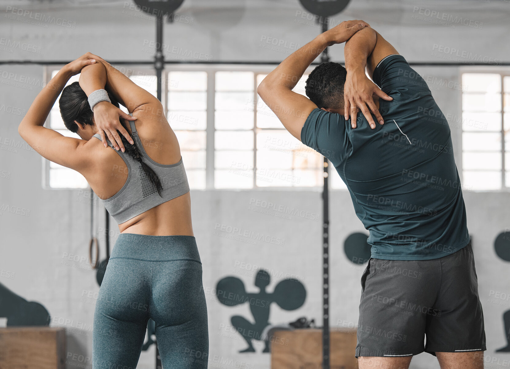 Buy stock photo Active, sporty fitness couple stretching or gym partners and friends getting ready to exercise together. Back view of male trainer and female athlete standing and doing warm ups before workout class.