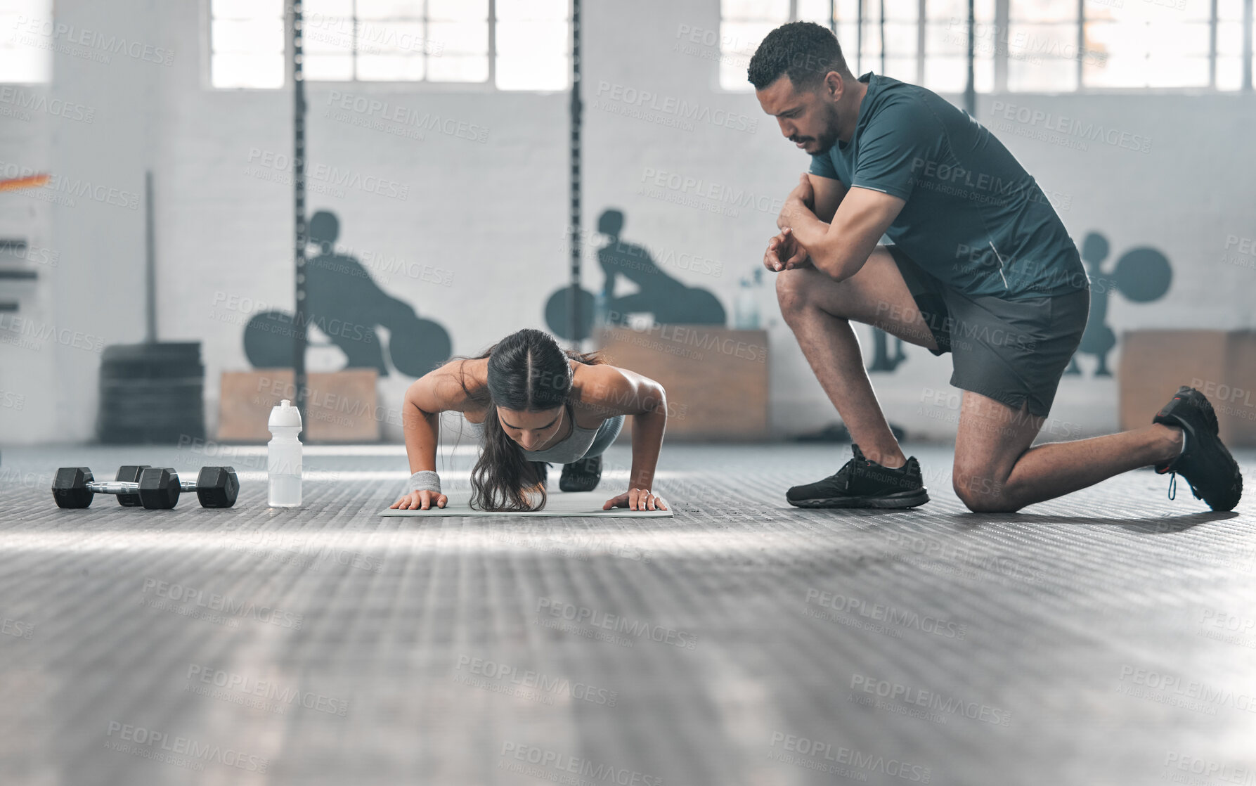 Buy stock photo Fit and athletic woman training with her personal trainer at the gym. An active female athlete doing pushups with her coach for her morning workout routine at a fitness and exercise facility