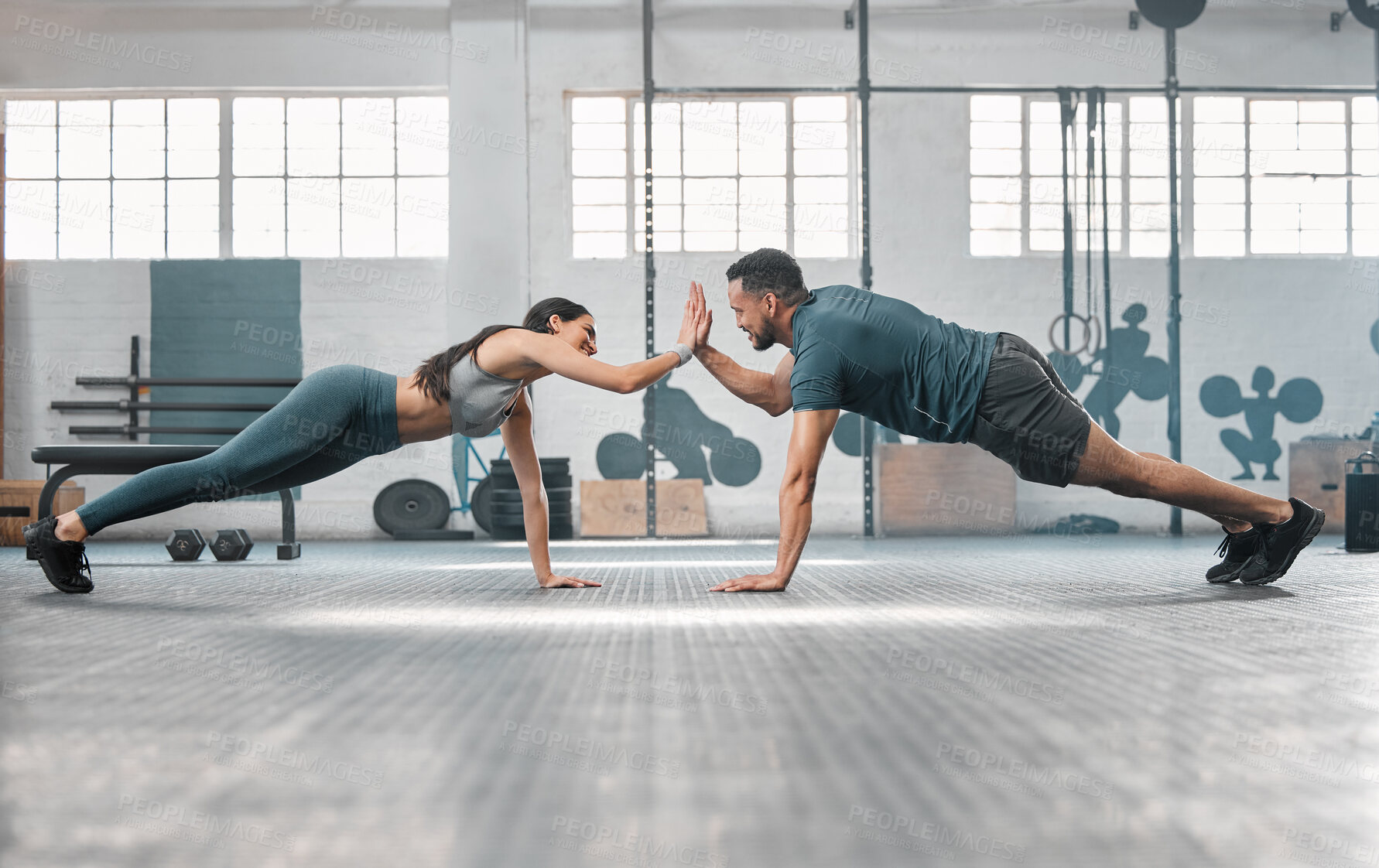 Buy stock photo Fitness partners exercising together and doing pushups high five at the gym. Fit and active man and woman training in a health facility as part of their workout routine. A couple doing an exercise