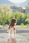 Happy carefree young woman on holiday enjoying the sunlight walking next to a forest. Carefree woman enjoying her holiday walking in the sunlight by a forest