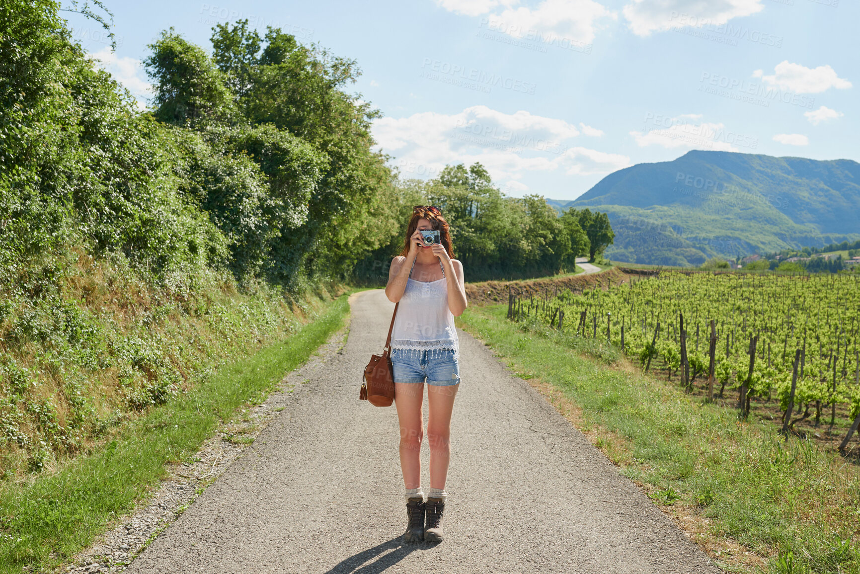 Buy stock photo Woman, tourist and camera with road in nature for sightseeing, memory or travel adventure. Young, female person or traveler with photography on street or path in countryside for picture or holiday