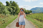 Woman on holiday alone taking photo of the countryside on her digital camera. Woman next to a vineyard taking photos on her digital camera. Woman taking photos during her holiday to the countryside