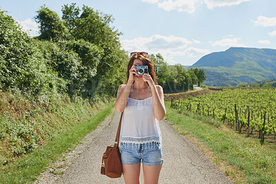 Buy stock photo Woman, travel and camera with road in nature for sightseeing, memory or outdoor adventure. Young, female person or tourist with photography on street or path in countryside for picture or holiday