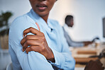 Closeup of one stressed african american businesswoman suffering with arm and shoulder pain in an office. Entrepreneur rubbing muscles and body while feeling tense strain, discomfort and hurt from bad sitting posture and long working hours at desk