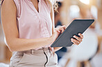 Close up of a business woman's hands using a digital tablet in an office. Woman browsing on the internet or interacting with clients on social network
