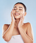 Closeup face beautiful young mixed race woman. Attractive female touching her face in studio isolated against a blue background. A skincare regime to keep your skin soft, smooth, glowing and healthy