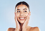 Closeup face beautiful young mixed race woman. Attractive female touching her face in studio isolated against a blue background. A skincare regime to keep your skin soft, smooth, glowing and healthy