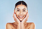 Closeup face beautiful young mixed race woman. Attractive female touching her face in studio isolated against a blue background. A skincare regime to keep your skin soft, smooth, glowing and healthy