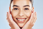 Closeup face beautiful young mixed race woman. Attractive female touching her face in studio isolated against a blue background. A skincare regime to keep your skin soft, smooth, glowing and healthy