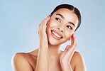 Closeup face beautiful young mixed race woman. Attractive female touching her face in studio isolated against a blue background. A skincare regime to keep your skin soft, smooth, glowing and healthy