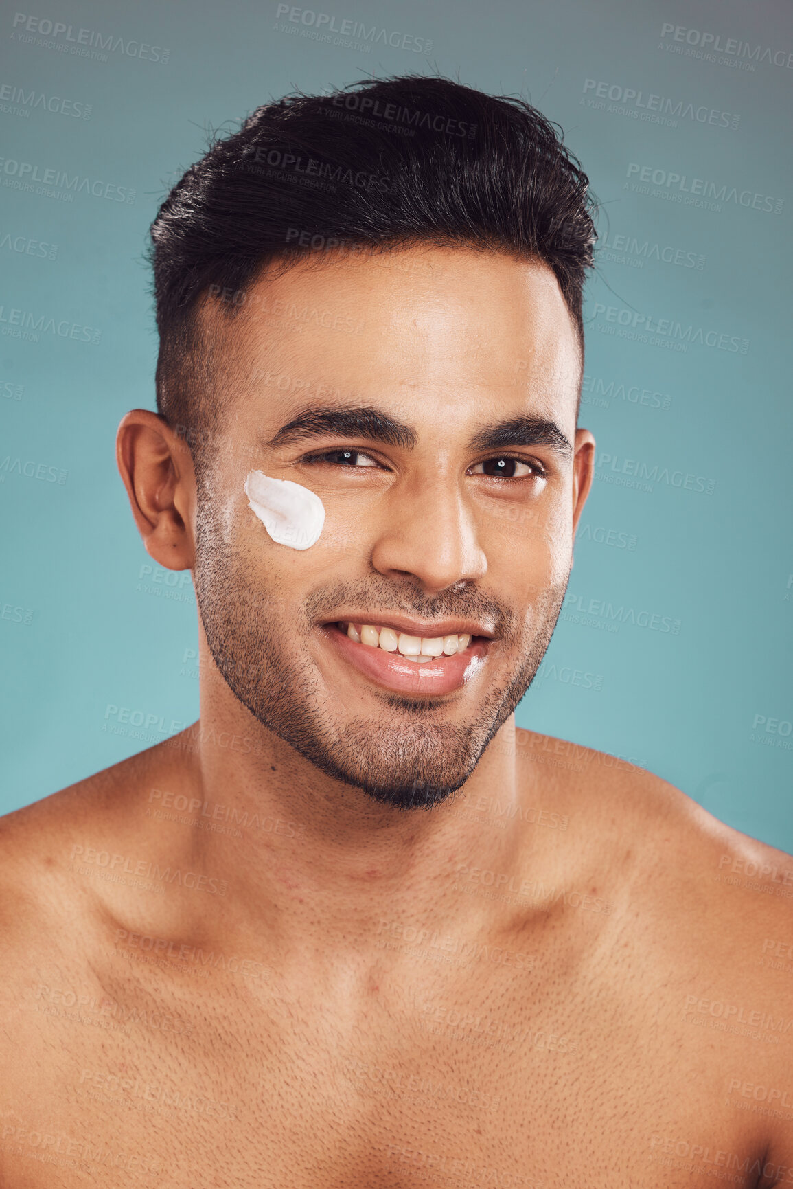 Buy stock photo Man, cosmetics and face cream in studio portrait for smile, pride or moisturizer by blue background. Person, model and happy with serum for facial glow, skincare or dermatology for health in Colombia