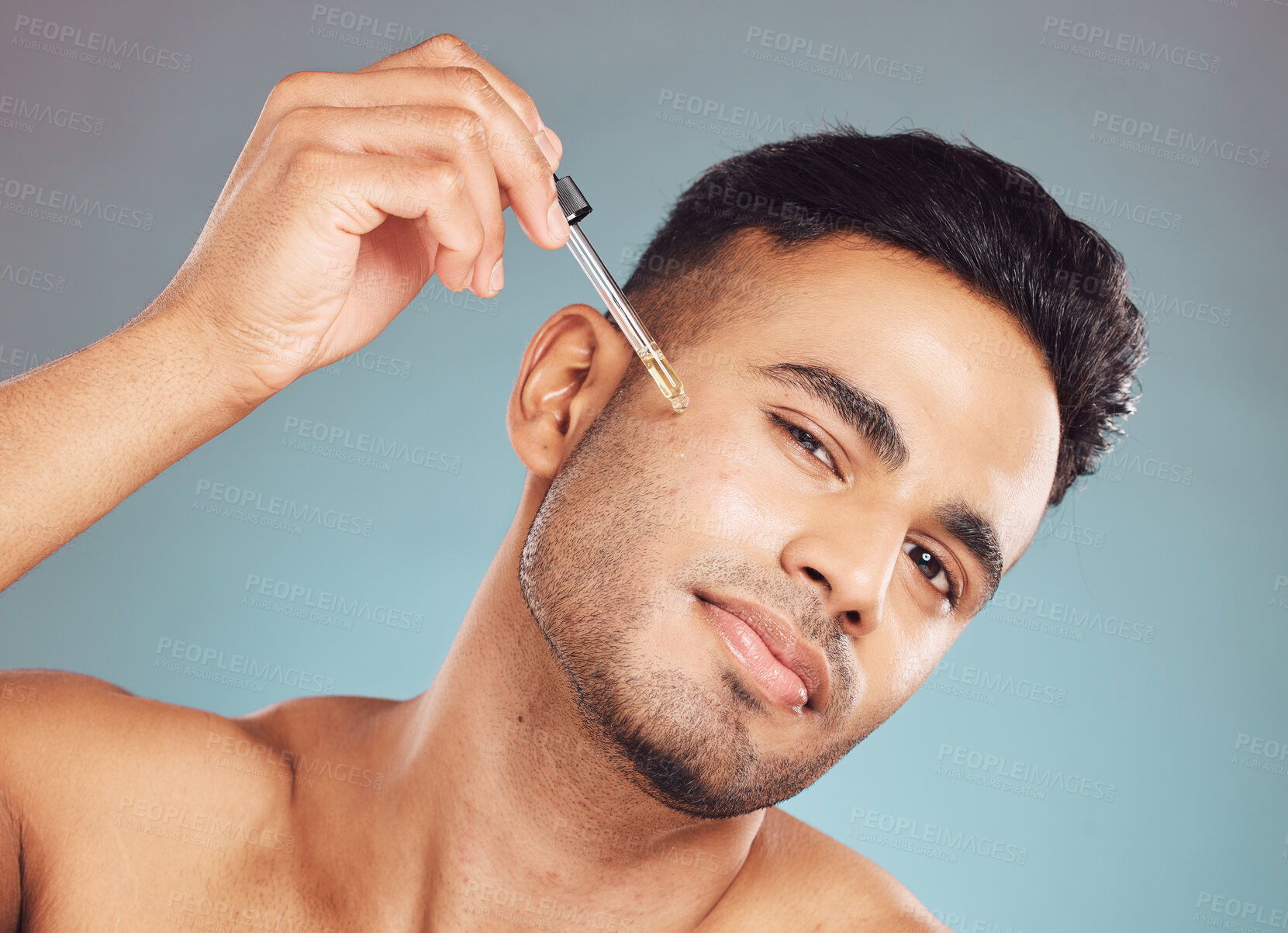 Buy stock photo Skincare, portrait and man with serum in pipette, facial treatment product or skin glow on blue background. Cosmetics, retinol and male person with oil, hyaluronic acid or collagen solution in studio