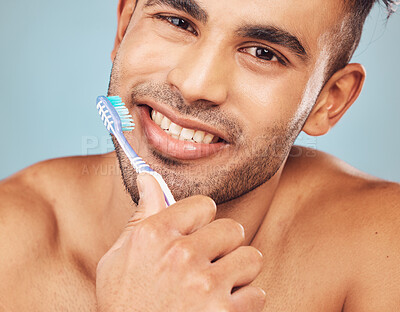 Buy stock photo Man, brushing teeth and smile in studio portrait for self care, hygiene or oral wellness by blue background. Person, model and toothbrush for grooming, happy and cleaning mouth for health in Colombia