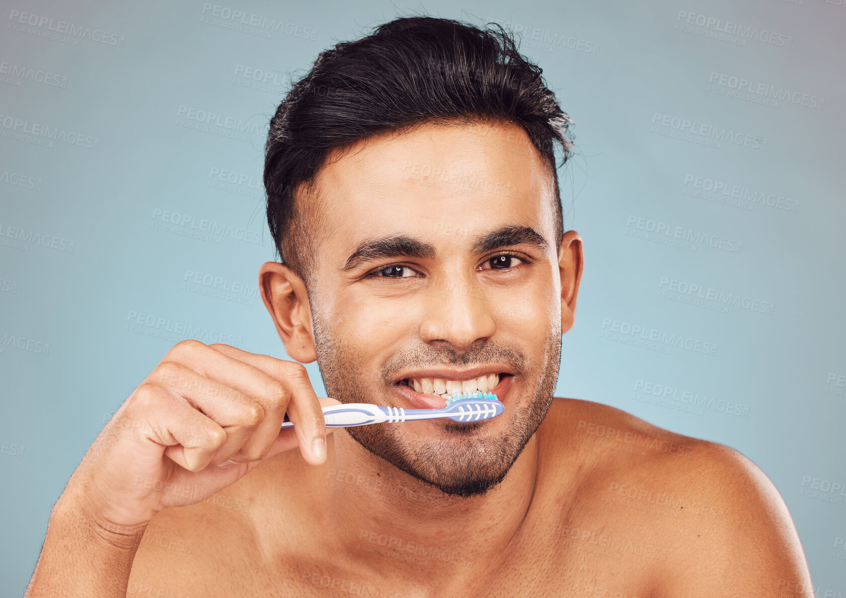 Buy stock photo Man, brushing teeth and happy in studio portrait for self care, hygiene or oral wellness by blue background. Person, model and toothbrush for grooming, smile and cleaning mouth for health in Colombia