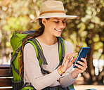 Hiking, phone and woman checking gps or online map in a forest, happy, relax and navigation. Nature, adventure and smiling woman exploring the woods, sitting to text and read message on smartphone