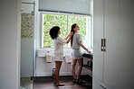 Happy women in bathroom, girl helping with hairstyle aesthetic and apply skincare together in luxury hotel. Looking in the mirror, beautiful friends with daily facial treatment and self care routine