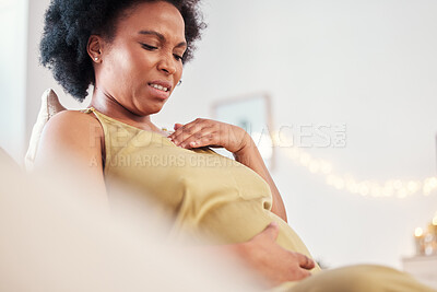 Buy stock photo Pregnant black woman on sofa with pain, cramps and stress sitting in living room with hands on stomach. Pregnancy, labour and mother on couch holding belly with ache or medical emergency in apartment