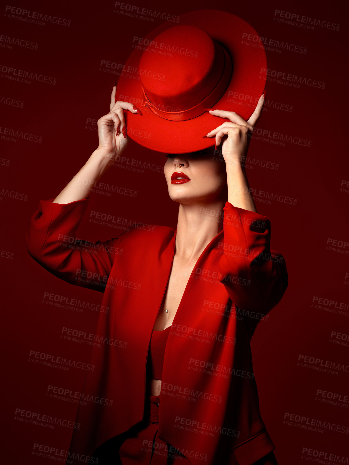 Buy stock photo Hat, fashion and a model woman on a red studio background for elegant or trendy style. Aesthetic, art or confidence with a young female person in an edgy and classy outfit, suit or clothes for beauty