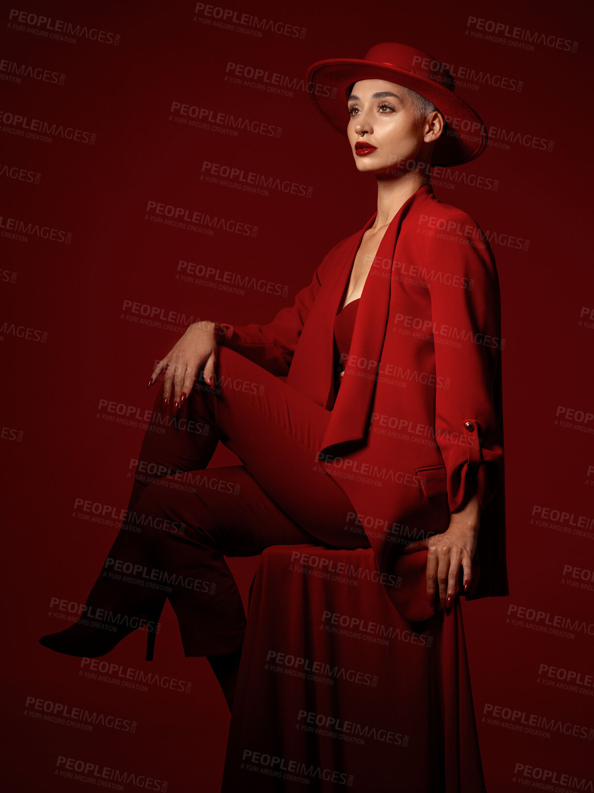 Buy stock photo Thinking, fashion and a woman sitting on a red studio background for elegant or trendy style. Vision, art and beauty on a chair with a young female model looking edgy or classy in suit clothes