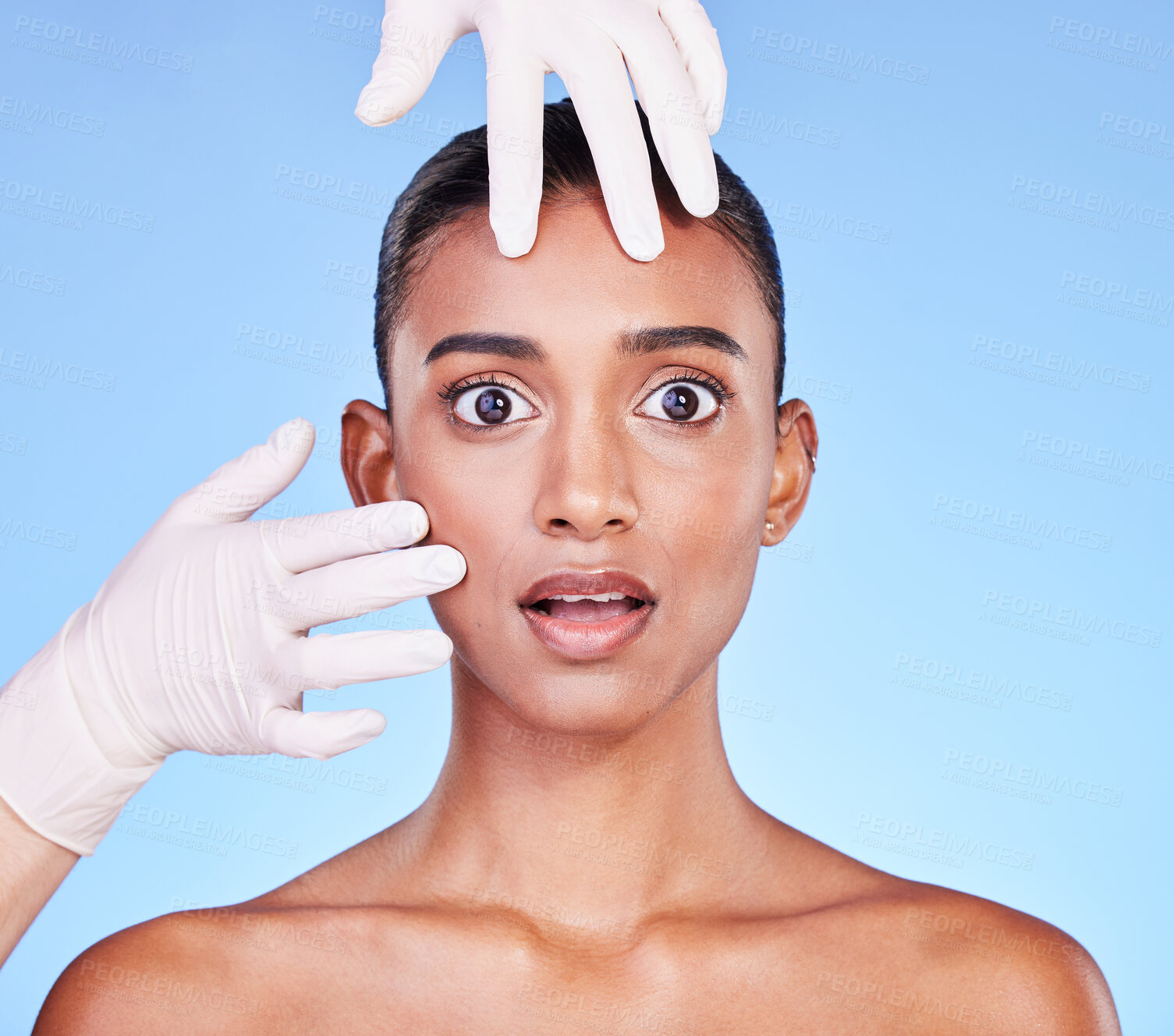 Buy stock photo Scared, doctor and portrait of Indian woman for plastic surgery, cosmetics and skincare in studio. Dermatology, shock and hands on face of person for anti aging, collagen and beauty on blue background